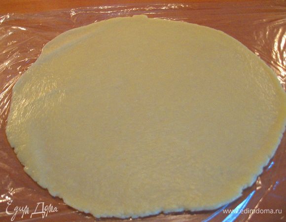 На плёнке, т.е. тесто кладём на плёнку и накрываем плёнкой, раскатываем большой кусок теста под размер формы. 
Снимаем пленку с верхней части раскатанного теста, а на нижней - аккуратно переносим его и переворачиваем в форму. Снимаем пленку. Делаем борта (3,5 см).