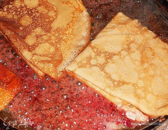 На скороду положить масло и сахар, затем влить вишневый сок и коньяк, погрузить блинчики, коньяк можно поджечь.  Перевернуть блинчики на другую сторону и добавить вишни (фрукты и ягоды можно использовать любые), обжарить немного и выкласть на тарелочку, сверху можно полить оставшимся сиропом.