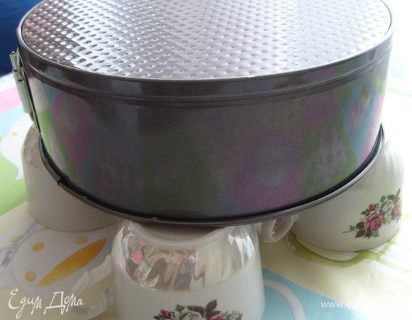 Готовый бисквит охладить в перевернутом состоянии. Для этого можно использовать решетку или взять четыре одинаковые чашки и на них положить перевернутую форму с бисквитом.