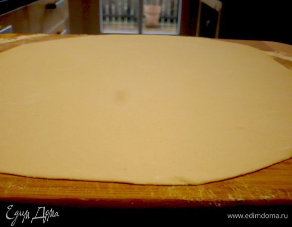 Разогреваем духовку до 200 градусов. Берем первый кусочек теста (лучше всего сразу отделить от него небольшой кусочек для верхушки пирога, накрыв его полотенцем, я этого не сделала и снимала потом края уложенного в форму теста, но раскатывать уже раскатанное тесто сложнее) и раскатываем его в круг диаметром примерно 28 см на присыпанной мукой поверхности.