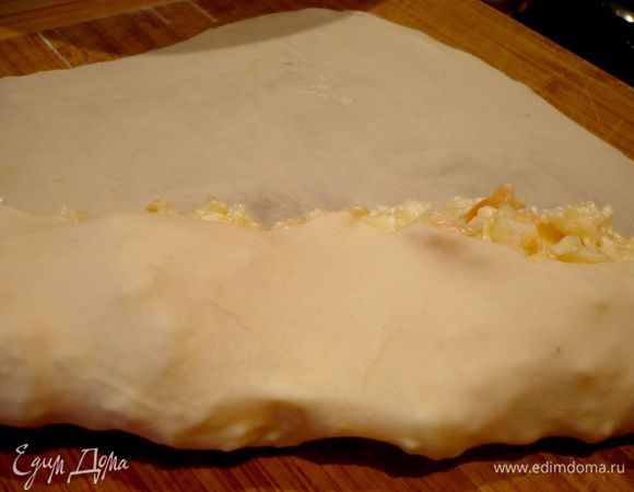 Достаем из холодильника следующий кусочек теста, делим его на четыре части и также тонко раскатываем сначала первый кусочек, растягиваем его, кладем на краешек пару ложек начинки и сворачиваем в рулет. Кончики рулета заворачиваем «конфеткой».