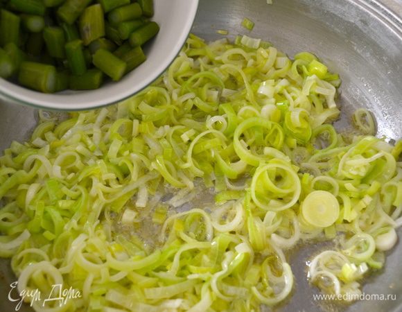 Как только лук станет мягким, добавить к нему порезанную кусочками спаржу и продолжить пассеровать еще несколько минут.
