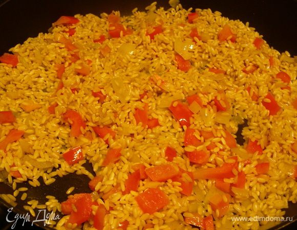 Перец режем кубиками и добавляем вместе с рисом в сковородку. Обжариваем все минуты 3-5, чтобы рис пропитался маслом.

