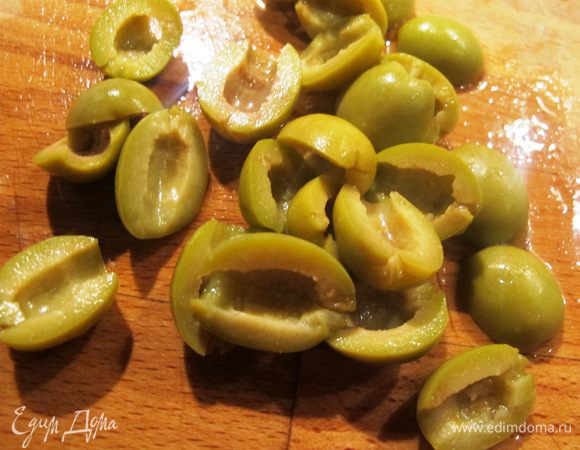 Оливки порезать напополам.