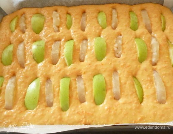 Форму для выпечки застелить пергаментом, смазанным маргарином и присыпать манкой. Вылить тесто для пирога и разровнять. У яблок удалить сердцевину, нарезать дольками и распределить по поверхности теста, слегка утопив. У меня осталось несколько колец ананаса и я часть яблок заменила ими. Получилось очень вкусно.