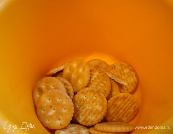 Орехи перемешать с дроблеными крекерами, 1/3 (или 1/4 ) массы отложить, а оставшиеся плотно утрамбовать в выстеленную пергаментом форму 22 см, поставить в холод