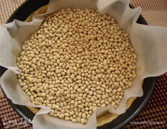 На тесто выложить бумагу для выпечки ( по размеру формы), сверху присыпать горохом или фасолью. Поставить в духовку на 20 минут. 