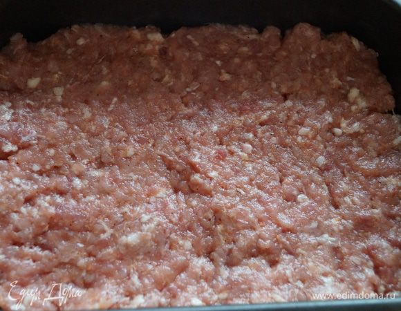 Дно формы для выпечки смажьте маслом и выложите мясной фарш ровным слоем.