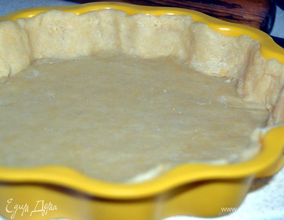 Охлажденное тесто раскатать на присыпанном мукой столе толщиной 4-5 мм. Форму смазать маслом и уложить тесто, сделав бортики.