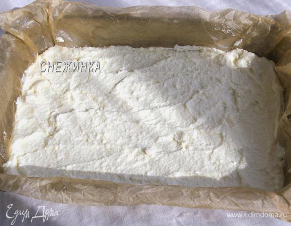 Подготовим прямоугольную форму для выпечки (у меня 26×18 см). Выстилаем её бумагой для выпечки и смазываем маслом. Чтобы бумага равномерно легла в форму, я смачиваю её в воде, хорошо отжимаю и распределяю по форме, она хорошо повторяет форму формы, затем смазываю. Распределяем нижним слоем творожную массу.