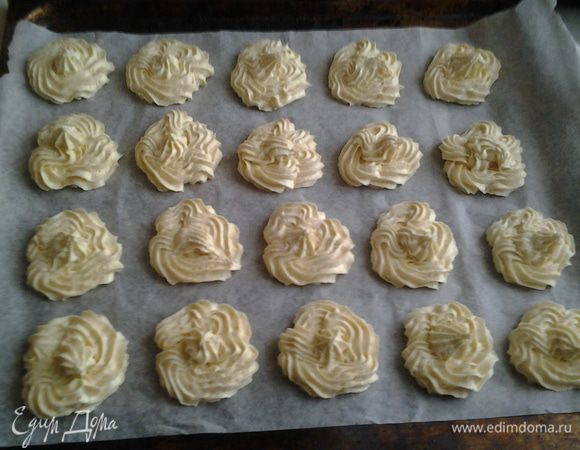 С помощью кондитерского шприца или просто ложкой выложить печенье на противень, застеленный бумагой для выпечки