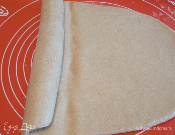 Выброженное тесто раскатайте в длинный, узкий пласт, скрутите тесто в рулет.