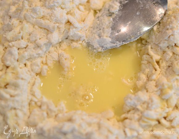 Сделать углубление в тесте и добавлять частями яичную смесь,перемешивая все ложкой.
