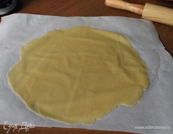 На обратной стороне противня (можно на силиконовом коврике или пергаментной бумаге) раскатать каждый шарик как можно тоньше.
Сверху положить тарелку (я использовала кольцо для торта диаметром 21 см), обрезать излишки теста ножом и наколоть вилкой, чтобы не вздувалось во время выпекания.
