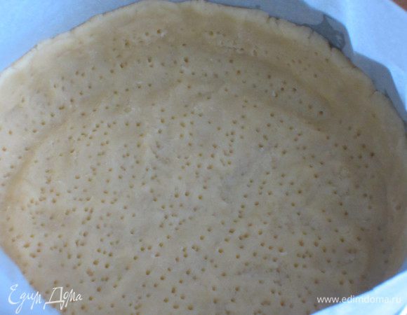 В разъёмную форму (диаметром 26 см) с пергаментом выложить тесто, сделав бортик 3-4 см.Тесто наколоть вилкой. Выпекать в предварительно разогретой до 180°С духовке ок. 15 минут.