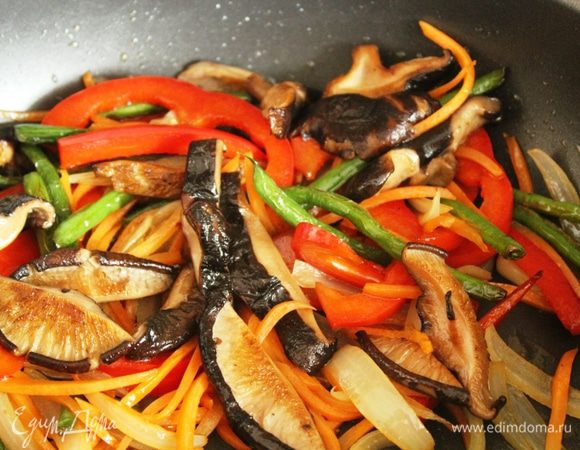 На этом же масле обжарить лук, морковь, болгарский перец, фасоль и грибы, добавляя их поочередно. Добавить креветки, хорошо перемешать, влить остатки маринада для загустения соуса, добавить крахмал и  кунжутное масло. 