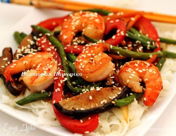 Сделать на тарелке "подушку" из рисовой лапши, на нее выложить обжаренные овощи и креветки, посыпать кунжутными семечками и немедленно подавать. Приятного аппетита!!!