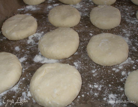 Муку просеять и, постепенно добавляя к творожной массе, замесить плотное, но нежное тесто. Взять кусочек теста руками, припудренными мукой, и скатать шарик размером с куриное яйцо. Выложить на противень, застеленный бумагой для выпечки, подальше друг от друга, потому что при выпечке сырники увеличиваются в размере. Сверху немного придавить рукой, чтобы получились достаточно толстые лепешки.