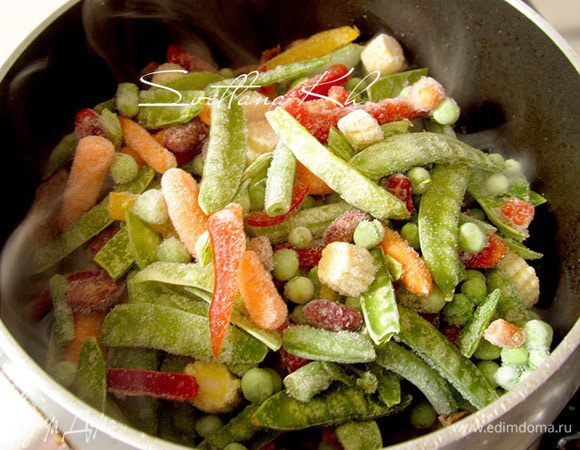 К мясу добавить смесь замороженных овощей, посыпать красным перцем. Тушить до полуготовности. 