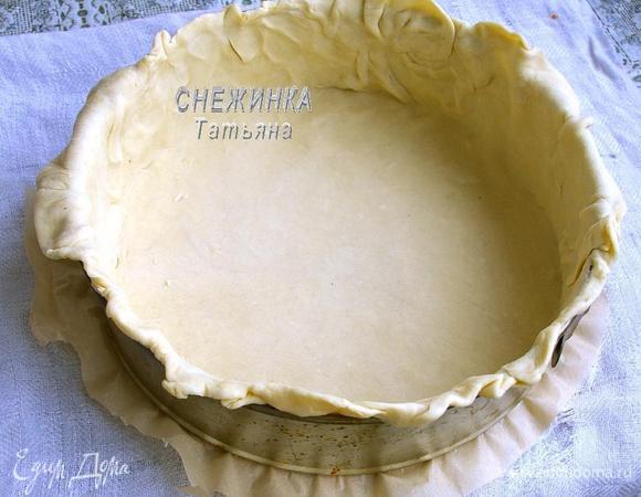 Слоёное тесто раскатываем на присыпанной мукой поверхности в тонкий круг. Он должен быть такой величины, чтобы сделать в форме бортики и ещё немного края свисали. Дно формы советую выложить бумагой для выпечки, прямо так, кладём квадрат бумаги и защёлкиваем кольцо. Раскатанное тесто выкладываем в форму и распределяем.