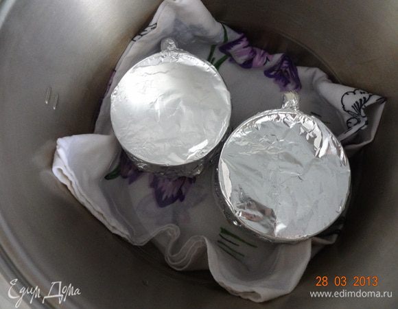 Поставить чашки на дно и налить теплой воды так, чтобы она немного не доходила до края чашки. Поставить кастрюлю на средний огонь, закрыть крышкой, дождаться момента закипания, убавить огонь до слабого и дать покипеть 1 минуту, затем огонь выключить, не открывая крышку, дать постоять пудингам 15 минут.