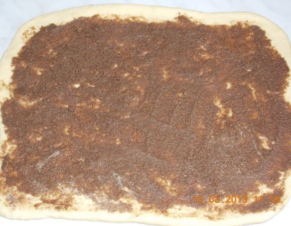 Когда тесто подошло, хорошенько его еще раз вымесить и раскатать в пласт толщиной примерно в 1см. Пласт теста смазать начинкой. 
Свернуть в тугой рулет. 