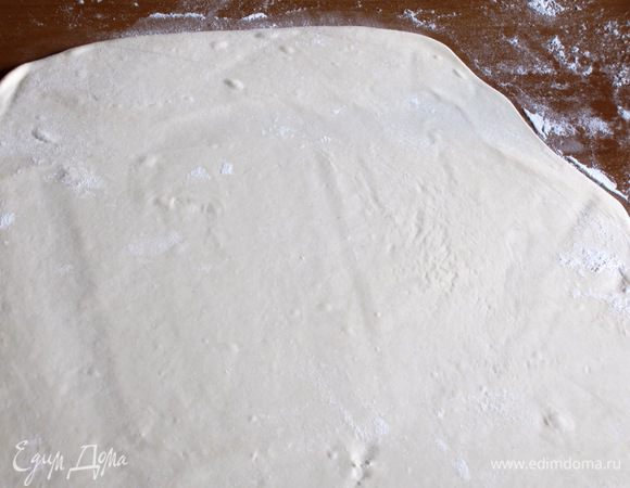 На присыпанном мукой столе очень тонко раскатать один шарик теста (300 г), затем осторожно растянуть его руками.