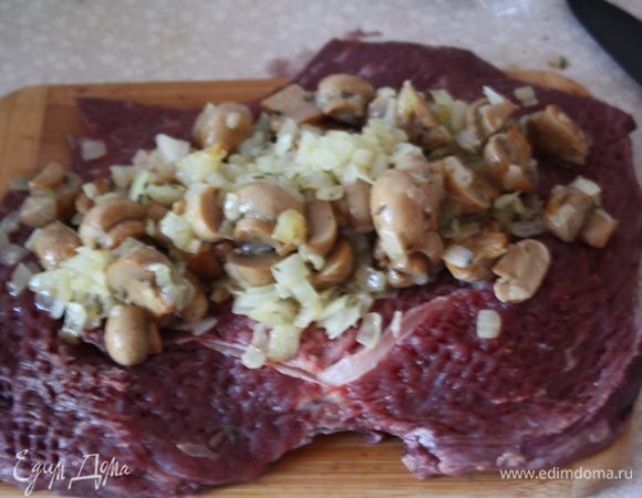 На отбитое мясо выкладываем грибы с луком и сворачиваем рулетом