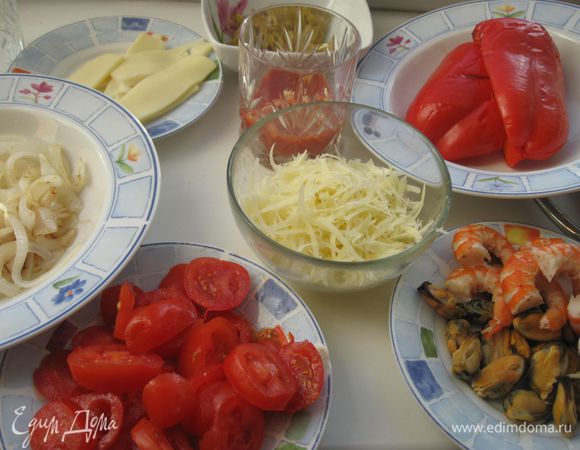 Лук нарезать тонкими полукольцами. Обжарить в масле. Сыр Пармезан натереть на крупной терке. Моцареллу порезать лепестками. Помидоры помыть, нарезать тонкими кольцами. Порезать оливки. Чеснок пропустить через пресс и добавить в пассерованные помидоры, посолить, поперчить. Креветки разрезать вдоль. Перец  очистить от семян, завернуть в фольгу, запечь в духовке, разогретой до 180°C 15 минут. Вынуть, дать остыть, нарезать небольшими продолговатыми треугольниками.