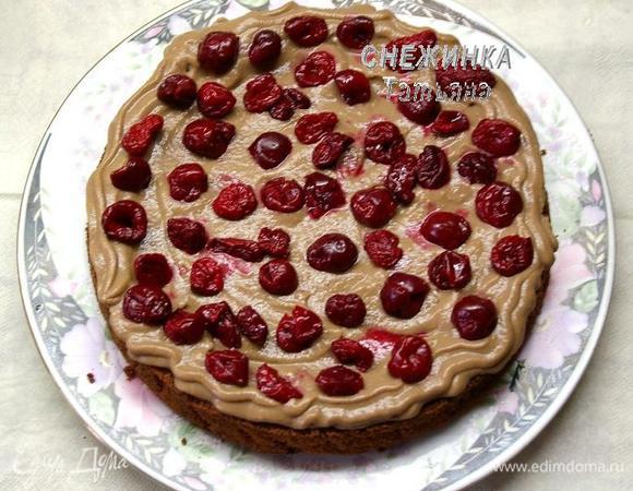 Сверху кладём слой крема. Исходите из расчёта крема на 4 коржа и немного для смазывания боков. Чтобы крем не вываливался через край коржа, рекомендую вначале выдавить по краю контур из крема с помощью кондитерского мешка, а затем ложкой выложить крем внутри, этот контур не позволит крему «убегать». На крем распределяем треть вишни, которую предварительно необходимо разморозить и сцедить жидкость, если она у Вас мороженая.

