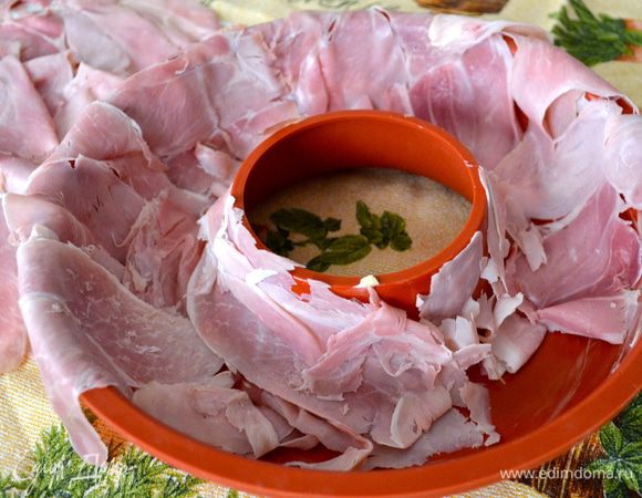 Форму с дыркой, в которой будем запекать пасту, смазать сливочным маслом и выложить всю полосками ветчины таким образом, чтобы края ветчины свисали с внешней стороны формы-кольца.  