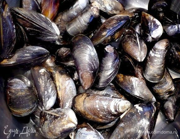 Сначала промоем каждую ракушку мидии под струей проточной воды, удаляя усики. Если при этом мы обнаружим открытые ракушки, попробуем стукнуть по ним легонько костяшкой пальца и, если они не закроются, удалим их. Я совершила ошибку, положив все ракушки (а уменя их было 2 кг) в не совсем холодную воду, в результате большая часть ракушек открылась и пришлось мне их отсортировать и просто отварить, так как выбрасывать было жалко, в суп их пустить я уже не решалась, хотя была уверена, что они раскрылись по моей оплошности. Так что не замачивайте ракушки в воде, да еще и нехолодной, а промывайте каждую из них постепенно под краном. 