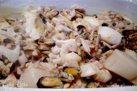 Смазываем форму для запекания сливочным маслом и выкладываем в нее рыбу и морепродукты с гребешками.
