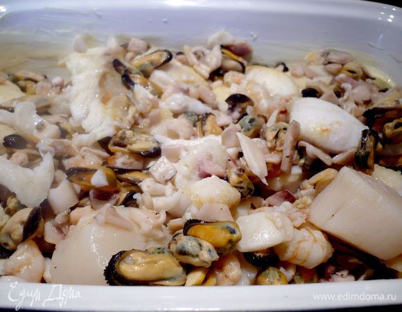 Смазываем форму для запекания сливочным маслом и выкладываем в нее рыбу и морепродукты с гребешками. 