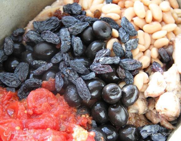 В глубокую посуду положите курицу, жареные лук и чеснок, нарезанные ломтиками помидоры, фасоль, маслины, изюм. Влейте 300 мл. воды. Доведите до кипения и убавьте огонь. Потушите под крышкой 15 минут, периодически помешивая.