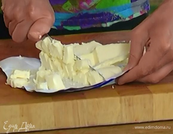 Приготовить тесто: предварительно охлажденное сливочное масло нарезать маленькими кубиками и выложить в чашу комбайна.