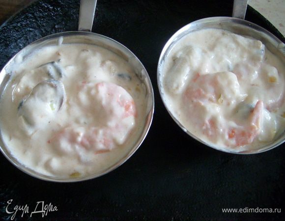 Выложить морепродукты с соусом в кокотницы, посыпать сыром и запекать в духовке 5-7 мин.