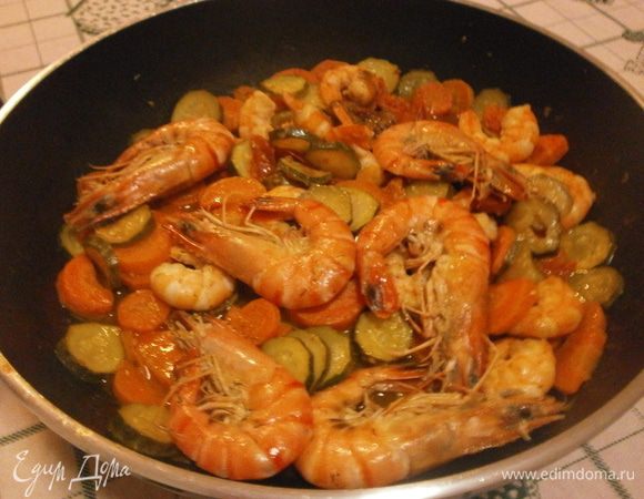 Выложить креветки в сковороду с овощами, накрыть крышкой и протушить 2-3 минуты. За это время смешаются вкусы нашего блюда. В это время можно подготовить и нарезать свежий салат.
