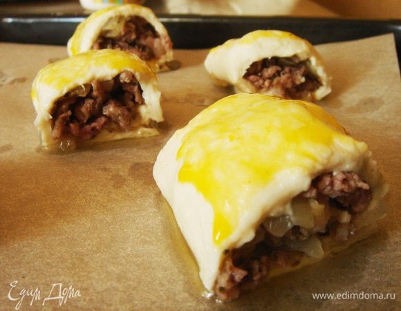  Тесто (у меня 2 листа по 250 г) разделить пополам. Из фарша слепить четыре колбаски по размеру теста. Выложить колбаски на тесто и завернуть рулетом. Разрезать каждый рулет на 4 части, выложить на противень, застеленный пергаментом. Смазать рулеты желтком. Выпекать 20 минут.