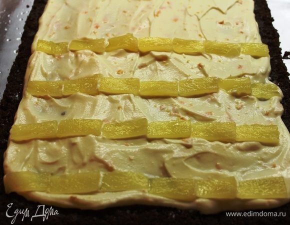 Выложить крем ровным слоем, оставив по краям примерно по 1,5 см. Кольца ананасов разрезать вдоль пополам, чтобы они были тоньше. Затем нарезать их тонкими пластинками и разложить поперечными полосками поверх крема