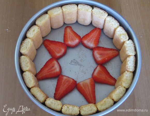 Каждую бисквитную палочку разрезать пополам и выложить ими бортик разъёмной формы (диаметр 20 см). Палочки следует ставить срезом вверх. Оставленную для украшения клубнику нарезать дольками и выложить на дно формы в виде цветочка. 