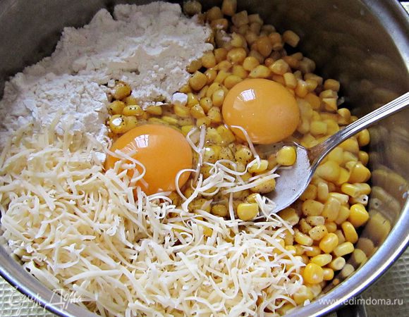 В кастрюльку с кукурузой добавить 2 яйца, 3 ст. л. муки, немного посолить, добавить щепотку сахара, перец и всё хорошо перемешать.
1/3 сыра добавить к кукурузной массе, а остальную часть оставить для посыпки.