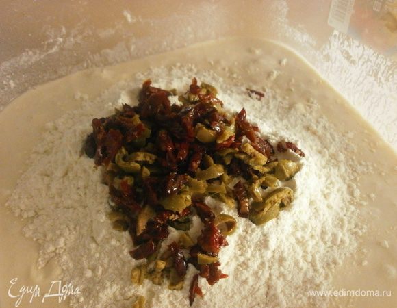 Добавить в тесто вяленые помидоры и оливки, 1 стол. ложку оливкового масла.Оставьте несколько оливок целыми для украшения. Т. к. помидоры и оливки достаточно солёные, необходимо регулировать количество соли. 