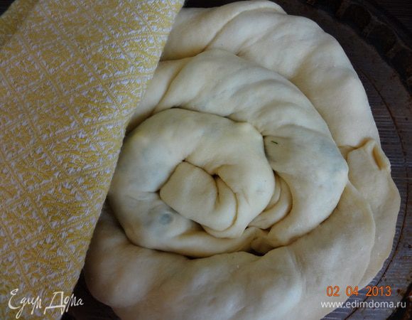 Форму (у меня 22 см.) смазать растительным маслом, выложить в нее рулеты, начиная от центра, закручивая по спирали, концы рулетов немного скрепить между собой. Оставить форму с пирогом в теплом месте на расстойку на 25-30 минут, прикрыв чистым полотенцем.