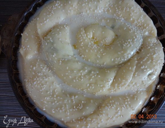 Через 25-30 минут, выросший пирог смазать оставшимся сливочным маслом, вылить заливку (яйца, молоко, соль и сахар взбить венчиком) и посыпать кунжутом. Отправить в духовку на 45-50 минут до румяной корочки.