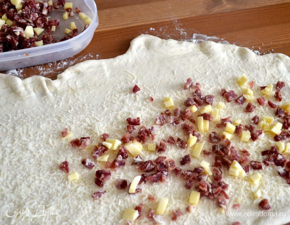 Сверху выложить порезанные кубиками салями, грудинку и сыр. Оставить один край теста свободным, чтобы удобнее было свернуть рулет.  