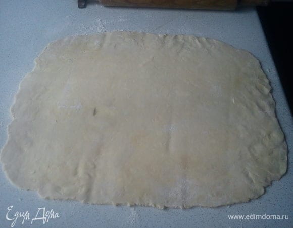 Тесто раскатать в тонкий пласт на посыпанном мукой столе. Я пеку пирог в прямоугольной форме, поэтому раскатываю пласт по размеру в два раза больше дна формы.