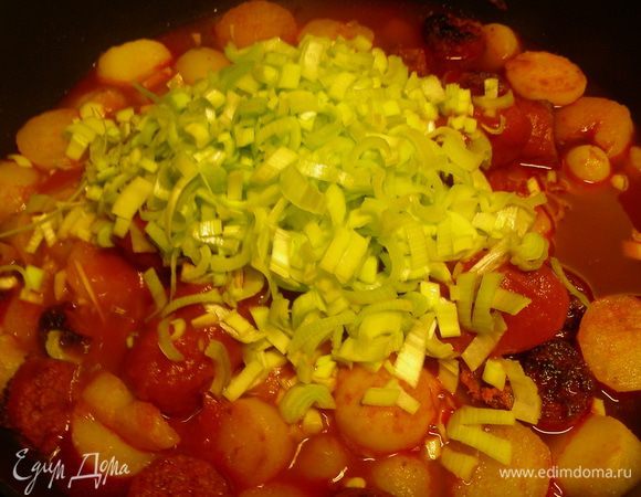 Добавляем томаты в собственном соку, порезанные кусочками и мелко порезанный лук-порей. Накрываем крышкой и готовим минут 10. При необходимости солим, перчим, но вообще это, скорее всего, не понадобится - чоризо дает богатый вкус.
