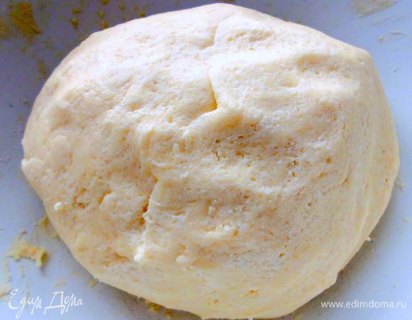 Добавить творог, муку, просеянную с разрыхлителем, и замесить гладкое мягкое тесто. Оно будет липнуть к рукам, но так и должно быть. Скатать его в шар, завернуть в пищевую пленку и отправить в холодильник на 1 час.