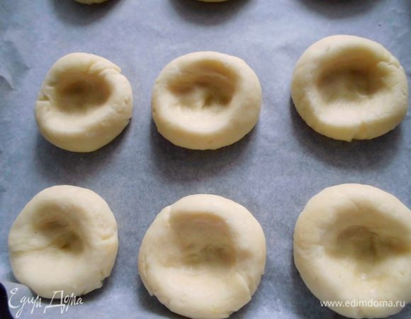 Тесто разрезать на небольшие кусочки и скатать из них шарики, размером с грецкий орех. Противень застелить бумагой для выпечки, выложить на него шарики, оставив между ними промежуток 2 см. Большим пальцем выдавить в середине каждого ямку. И немного пройтись пальцем ближе к краям, чтобы она стала больше.